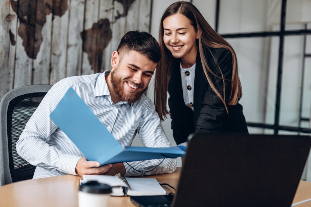 A smiling manager and his assistant work in the office