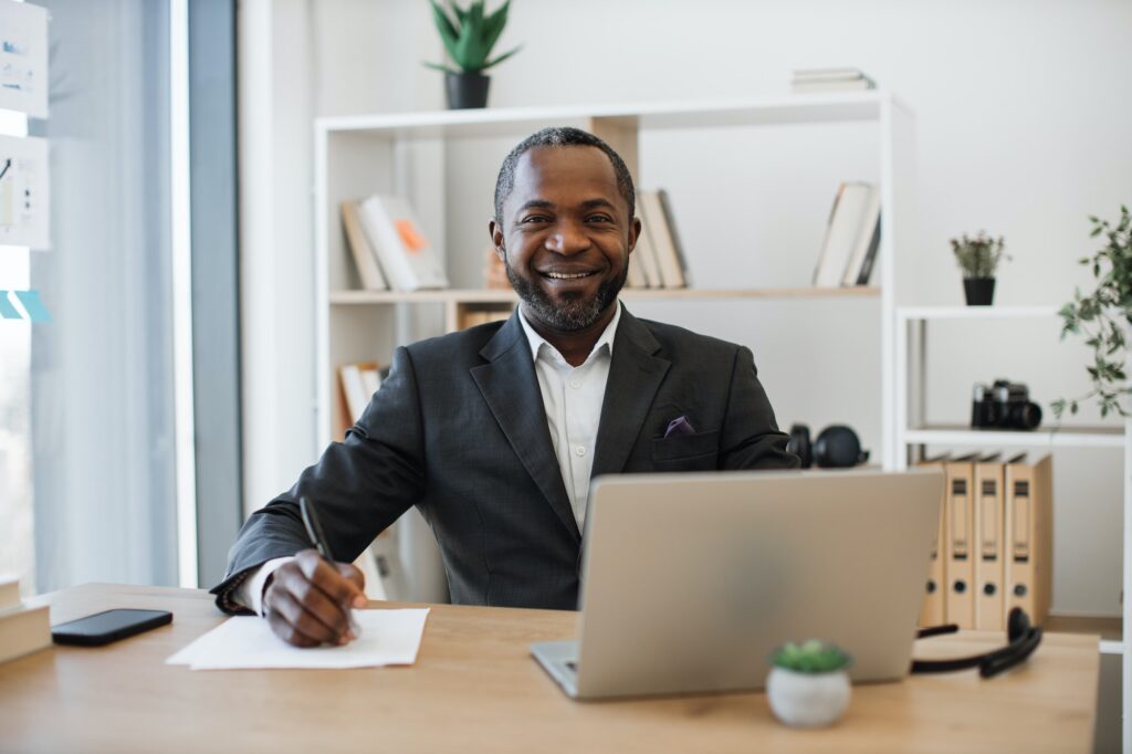 Office administrator sitting at writing desk with laptop