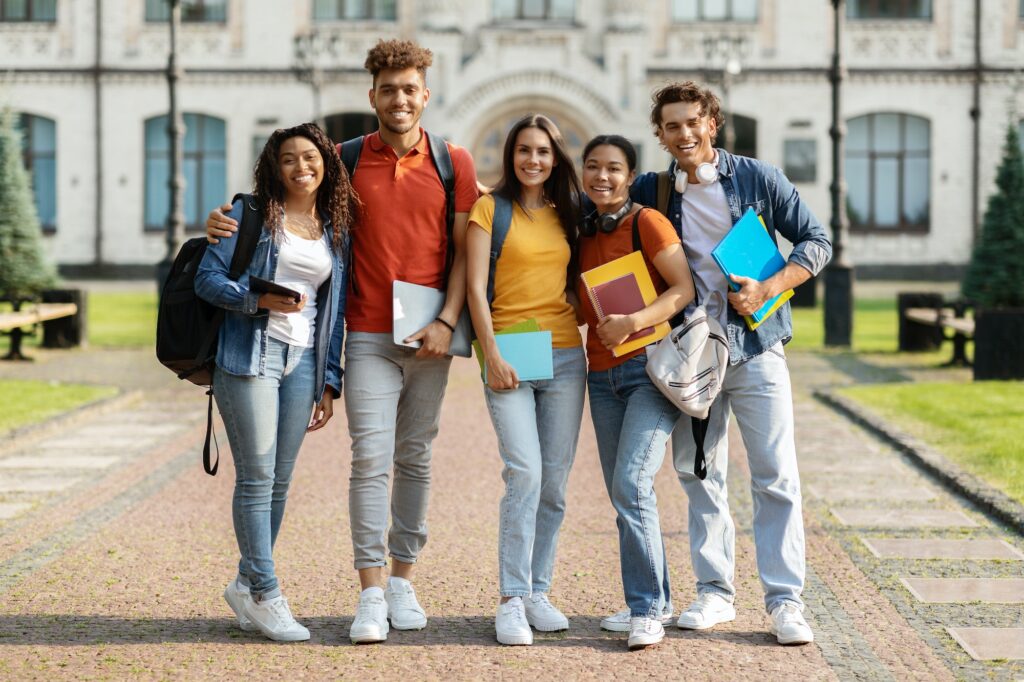 Portrait of happy international students posing outdoors near university building