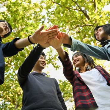 Group of university friends stacking hands together. Human relationship and back to school concept.