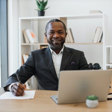 Office administrator sitting at writing desk with laptop