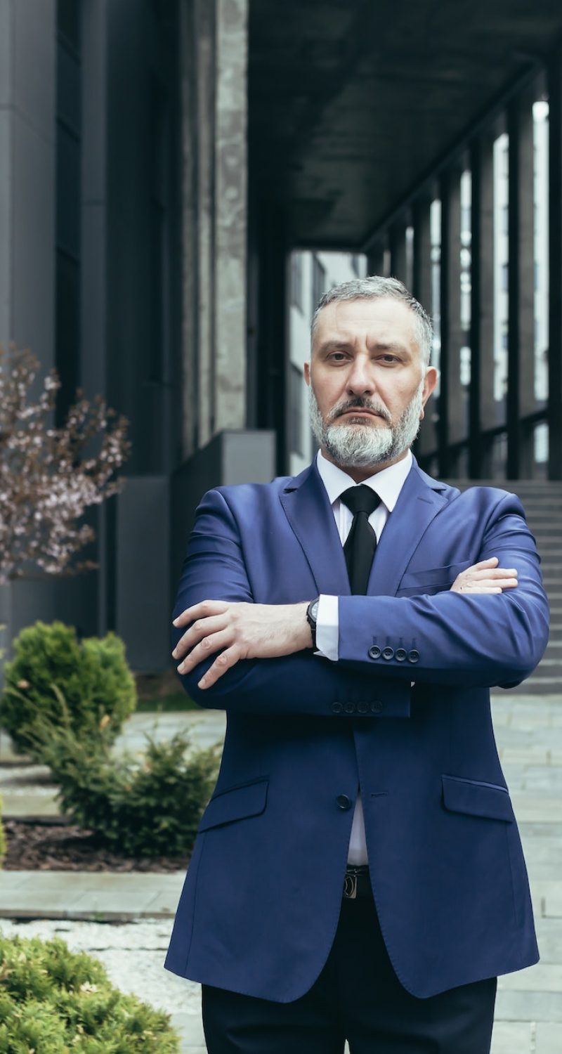 Portrait of senior handsome man, a businessman, a judge, a lawyer. Standing near the courthouse